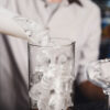 local bartender pouring ice in a glass