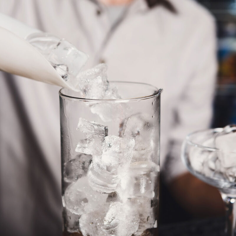 local bartender pouring ice in a glass